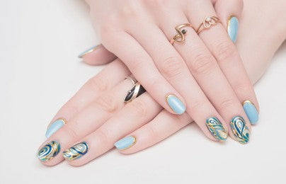 Girl's hand with a designed nail and a beautiful nail-art against a white background