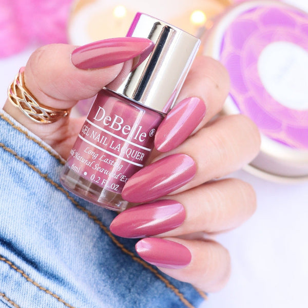 DeBelle Shimmer Dark Mauve Nail Polish Close-up view of the nail polish bottle and manicured nails has pink with white background 