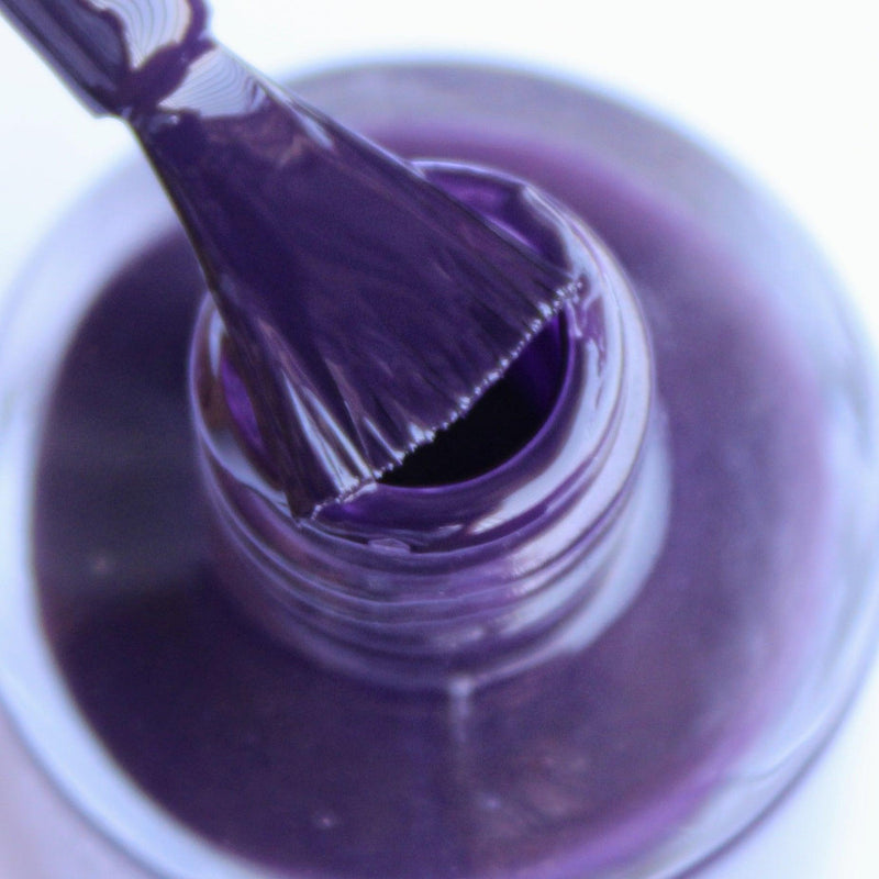 Close-in view of the nail polish bottle with the nail brush against a white background.