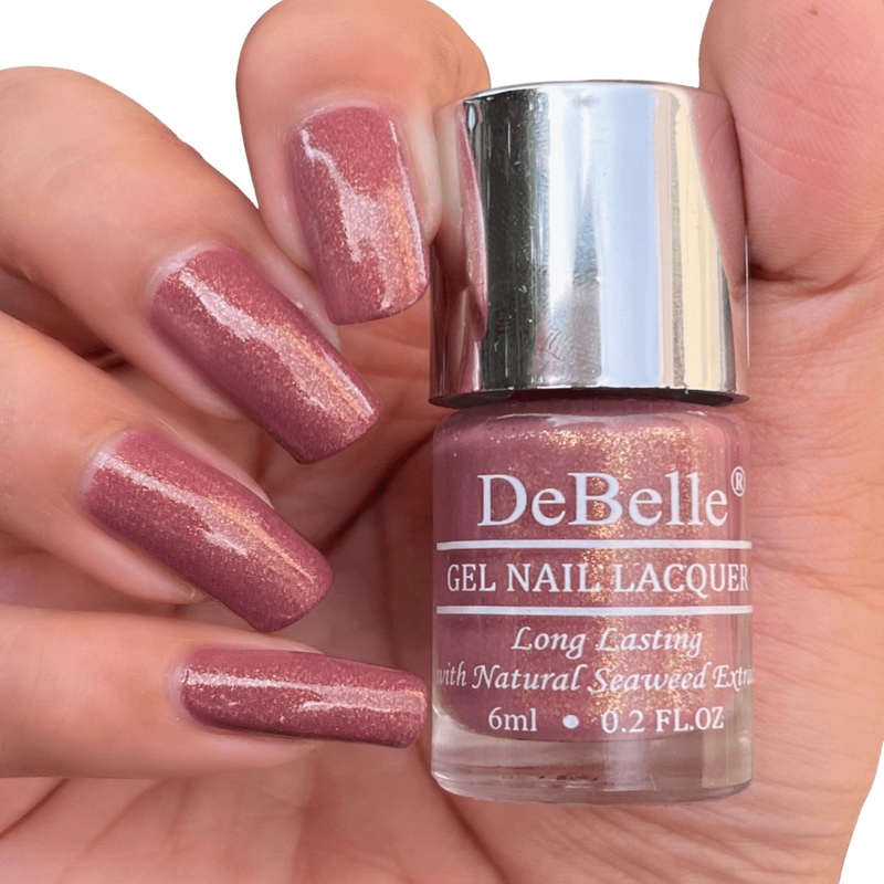 DeBelle Mauve with micro Shimmer Nail Polish Close-up view of the nail polish bottle and manicured nails has dark background 