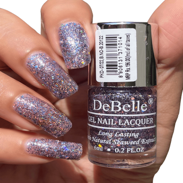 Holding Light purple Nail polish Bottle from Debelle with the painted nail of same shade against a dark background.