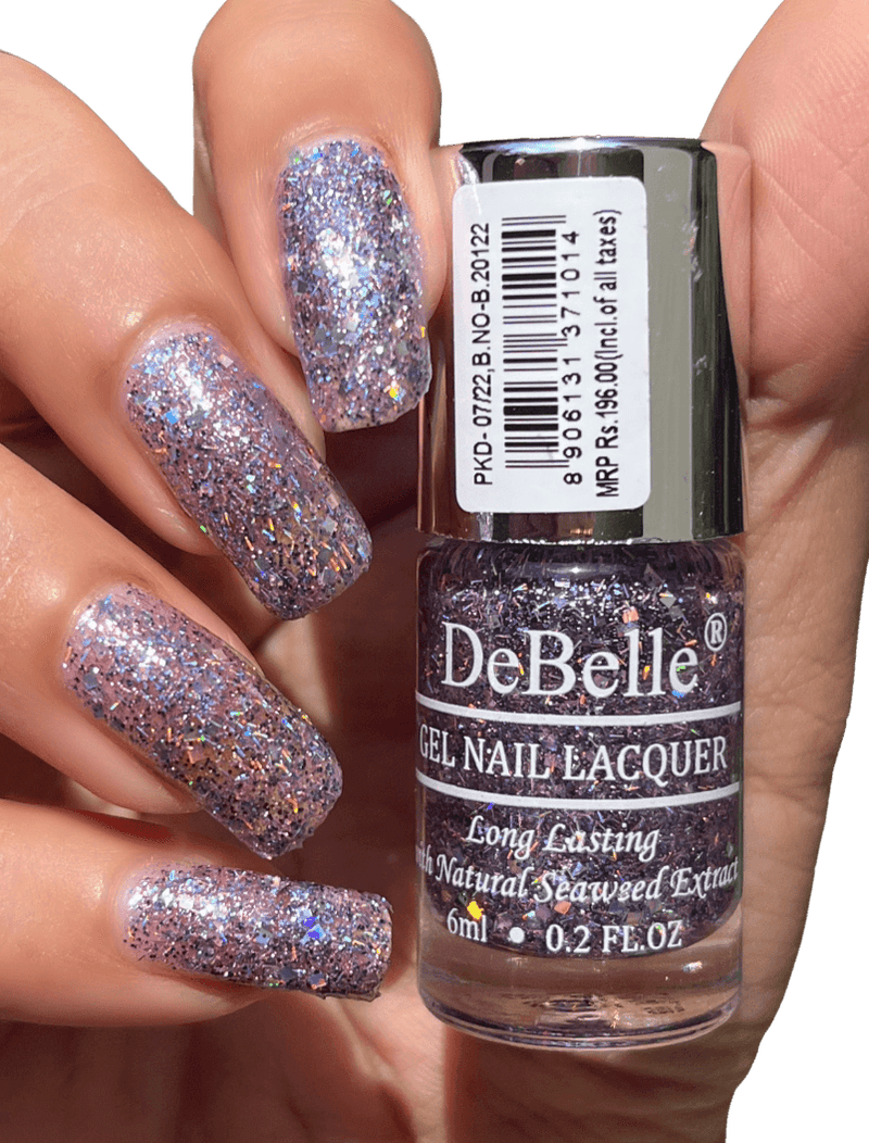 Holding Light purple Nail polish Bottle from Debelle with the painted nail of same shade against a dark background.