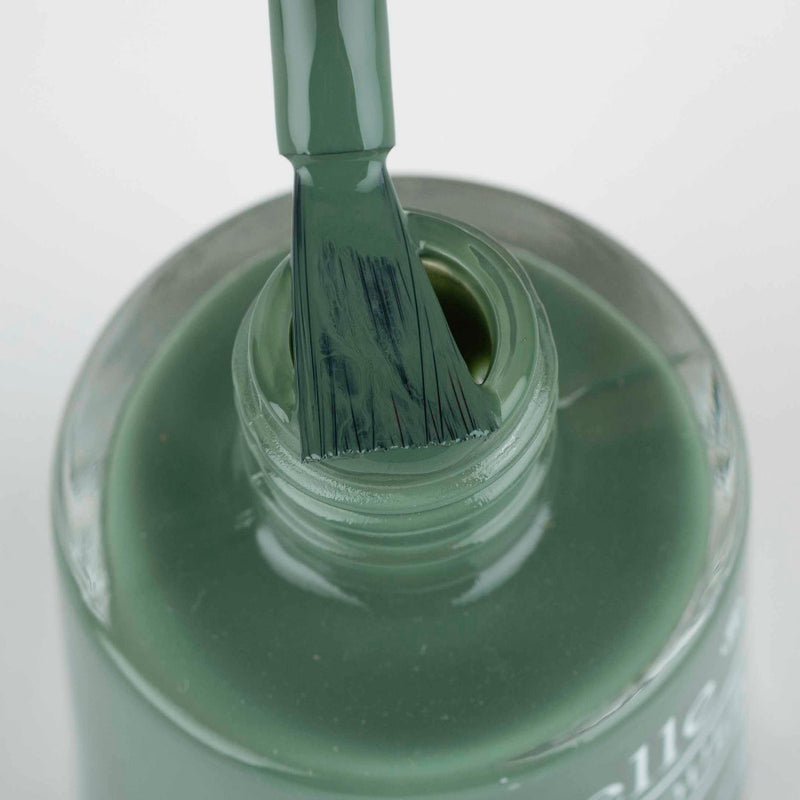 opened bottle of Debelle olive green nail polish with a nail brush. against a white background.