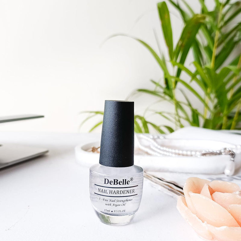 DeBelle Nail Hardner Bottle has white background with the plant in the background.