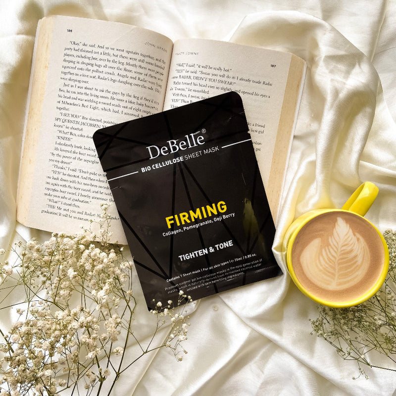 DeBelle Bio Cellulose Face Sheet Mask Firming placed Infront of a book with a yellow cup against a cream background 