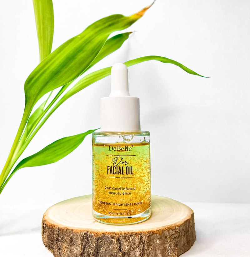 Debelle Golden Facial oil filled with oil placed against a white background and a green leaves to it.