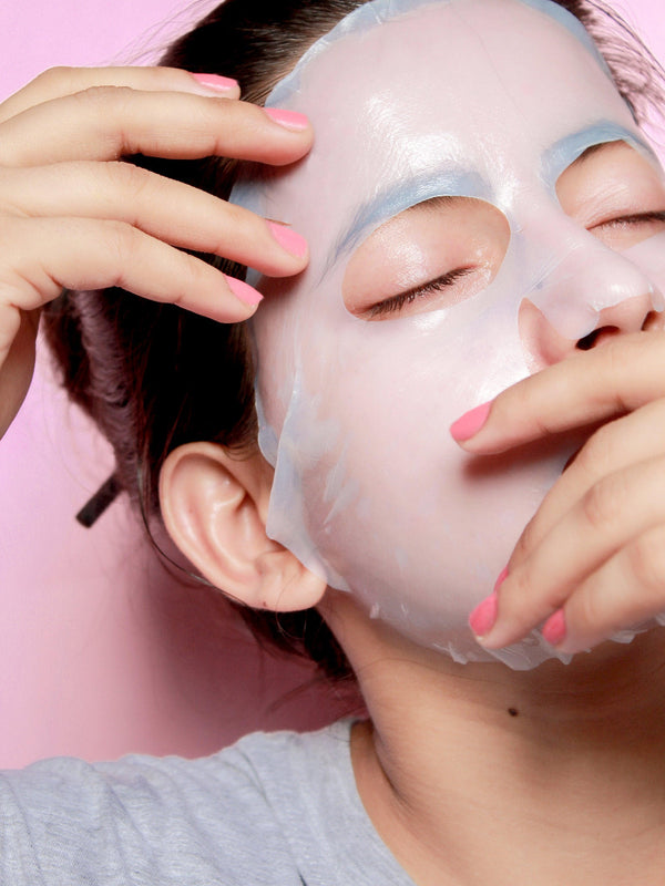 Women applying Debelle firming sheet masks against a pink backgrounf.