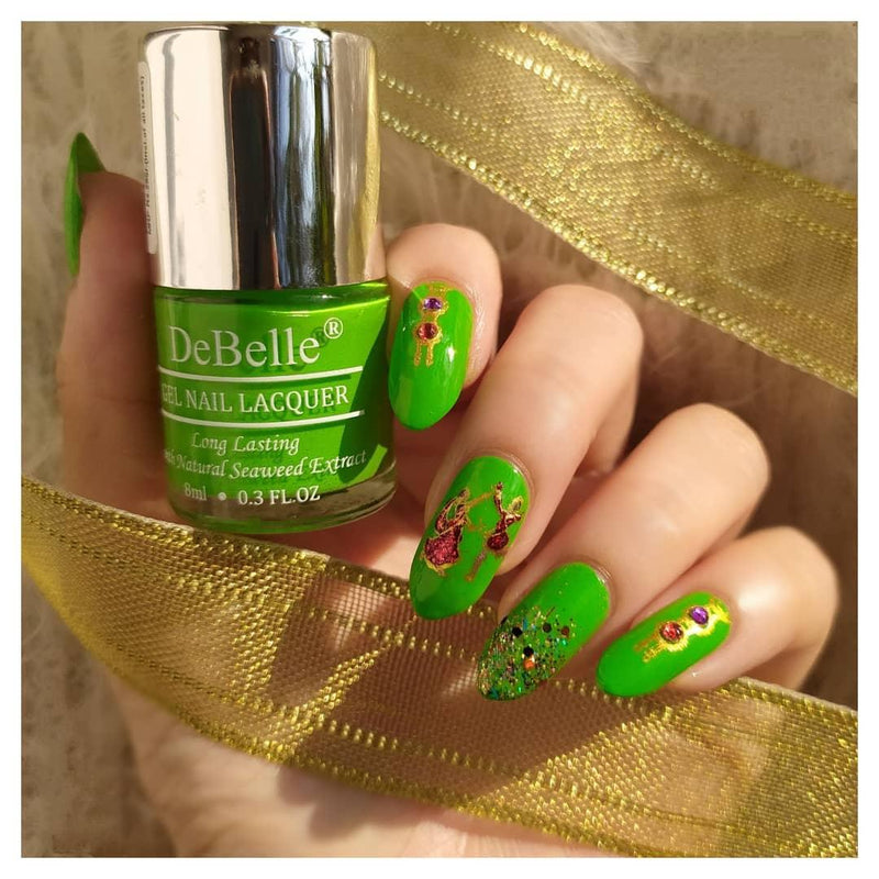 DeBelle parrot green -close-up view of nail polish bottle with the manicured nail with the elegance against white background with a golden ribbon.