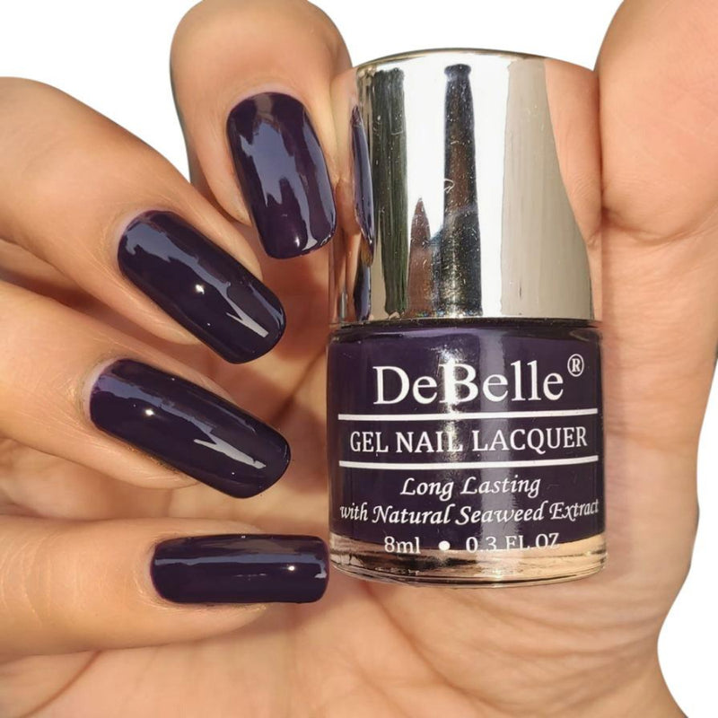 DeBelle Deep Violet Nail Polish - Close-up view of the nail polish bottle and manicured nails against a white background.