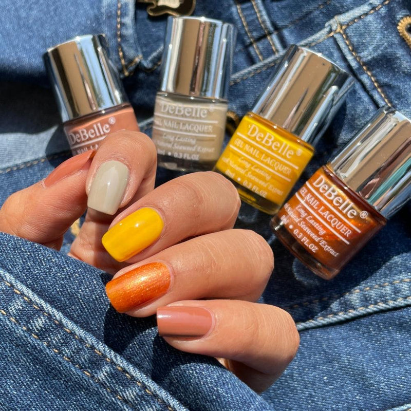Collection of Four Nail Polish which are Moonstone Bloom,Caramelo Yellow,Aurora & Toffee Rose from DeBelle with the painted Nails has blue jeans background