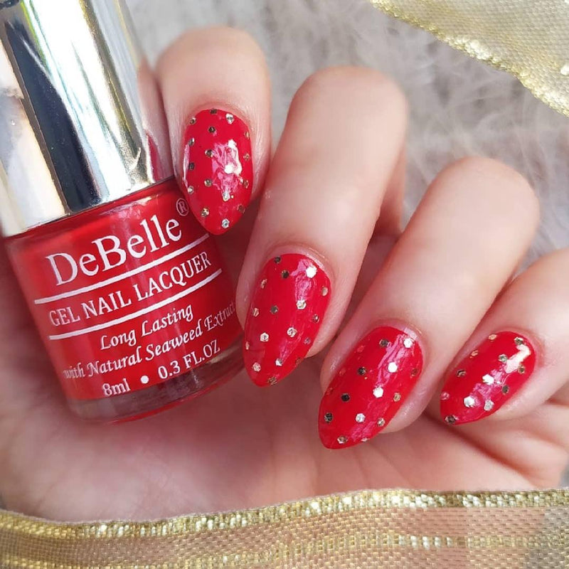 DeBelle Scarlet Red Nail Polish Close-up view of the nail polish bottle and manicured nails against a White background