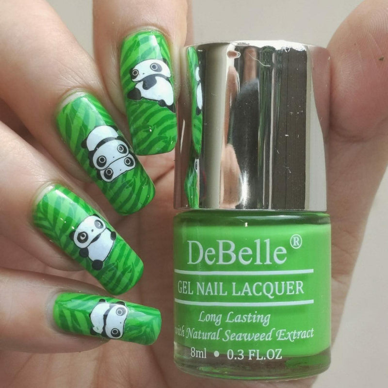 DeBelle parrot green -close-up view of nail polish bottle with the manicured nail with the elegance against white background.