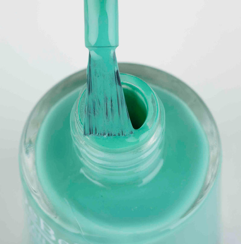 opened bottle of DeBelle Turquoise green nail polish bottle with a brush gainst a white backgroud.