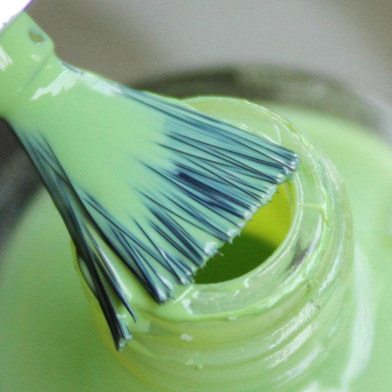 opened bottle of Debelle olive green nail polish with a nail brush. around a blurry background 