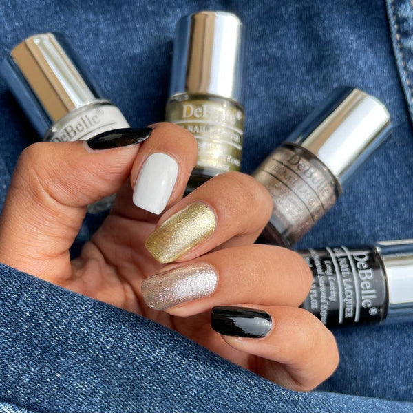 Collection of Four Nail Polish which are Vanilla Croissant, Canopus  Sparkling ,Dust Luxe & Noir from DeBelle with the painted Nails against blue jeans background